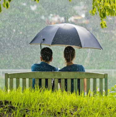Romantic-couple-sitting-in-park-while-raining-600x375