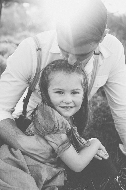 Happy beautiful family of three dad mom and little cute daughter portrait,  child girl smiling embracing mother and father posing with parents looking  at camera, kid hugging mommy daddy headshot Stock Photo |